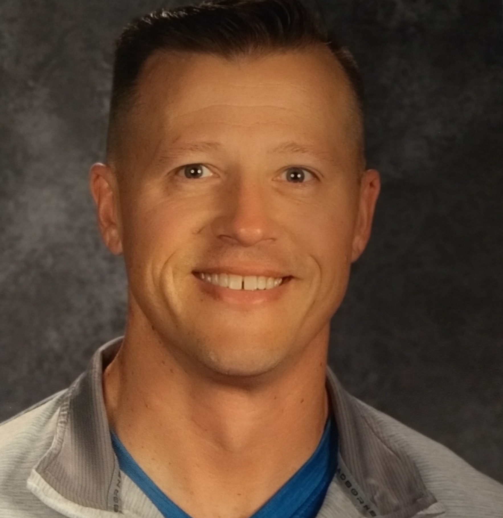 Asaptive sports: Headshot blonde man in tab jacket with bright blue t-shirt smiling into camera