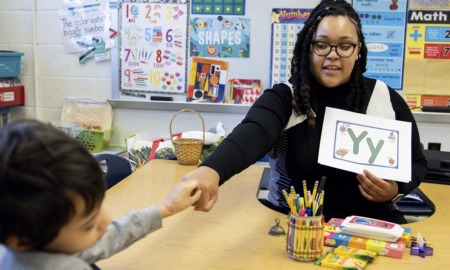 US teacher shortage, HBCU helping to change that: young Black female teacher fist bumps a student while teaching