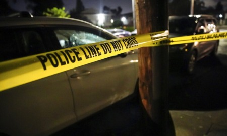 community youth gun deaths: crime scene tape in front of police car at night