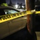 community youth gun deaths: crime scene tape in front of police car at night
