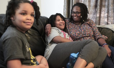 Autism now more common among Black, Hispanic kids in US: black family sitting on couch with mother hugging daughter while smiling