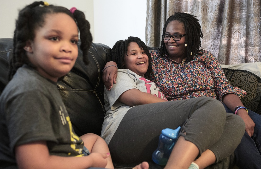 Autism now more common among Black, Hispanic kids in US: black family sitting on couch with mother hugging daughter while smiling