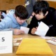 digital literacy, misinformation education: two young, male students looking at papers at table