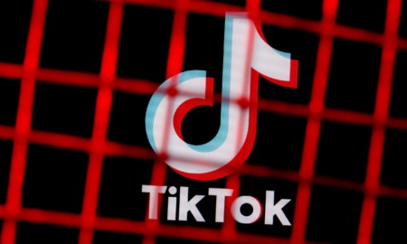 TikToc logo on black covered by red square mesh fencing