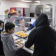 Hungry Kids: Elementay students stand in line adding food to their food trays in school cafeteria