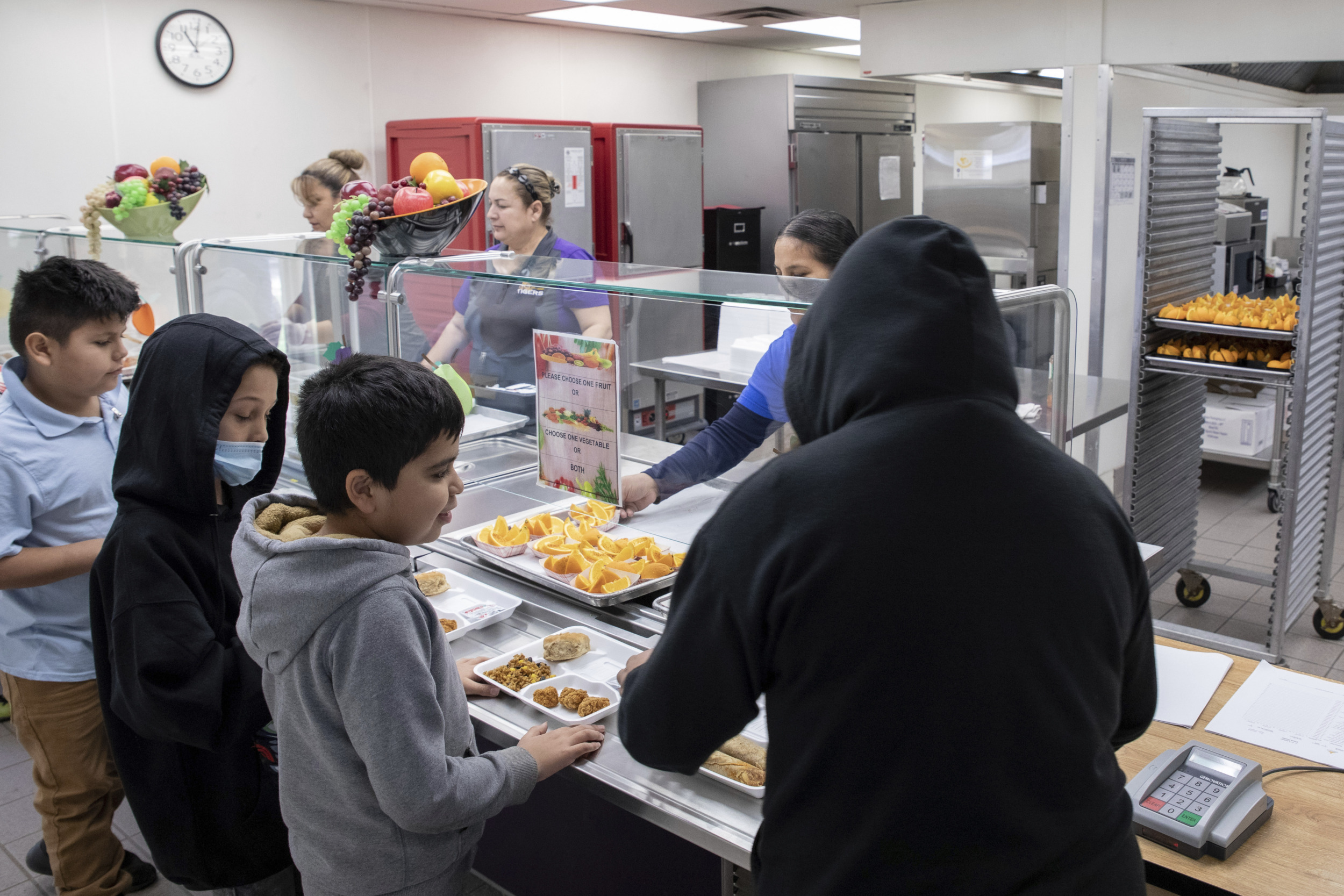 Hungry Kids: Elementay students stand in line adding food to their food trays in school cafeteria