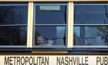 Covenant School shooting: Young blinde girl sits inside yellow school bus with face abd hand pressed against window crying