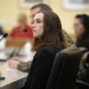 Surge in eating disorders spurs state legislative action: young woman with brown hair looks off to her left while seated at table with microphones