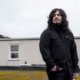 Community colleges are reeling. 'The reckoning is here.’: young man with long dark hair standing outdoors in dark jacket