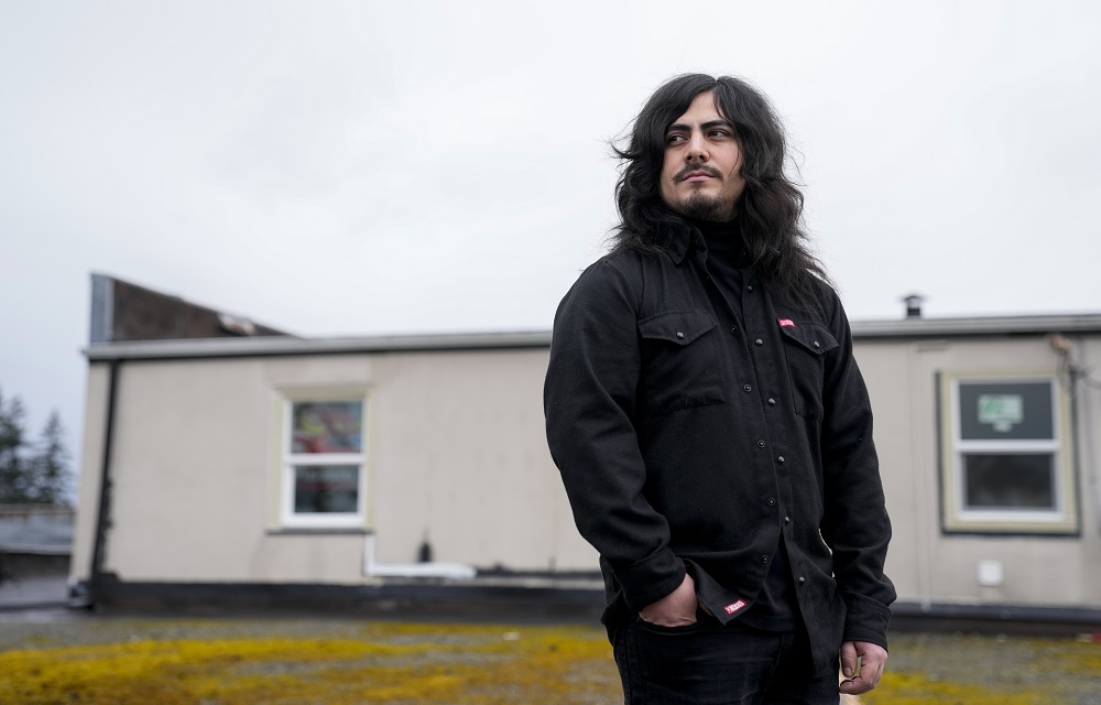 Community colleges are reeling. 'The reckoning is here.’: young man with long dark hair standing outdoors in dark jacket