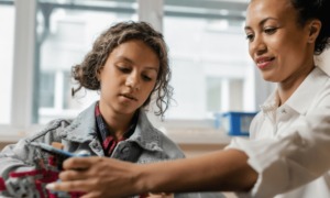 Gender education equity in STEM grants: woman and girl work on STEM project together
