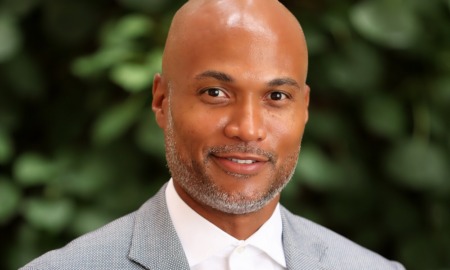 Jermaine Myrie named CEO of MENTOR: black, bald man with greying short beard wearing suit in front of out-of-focus plant backdrop
