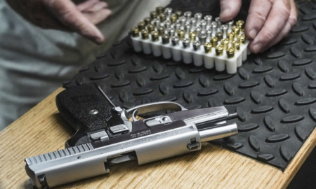Gun injury increase: Close up of a black and silver handgun lies next to a box of nearly 100 bullets on a table