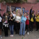 Brazil school violence: Middle school age children stand with fists raised and protest signs om front of red brick wall