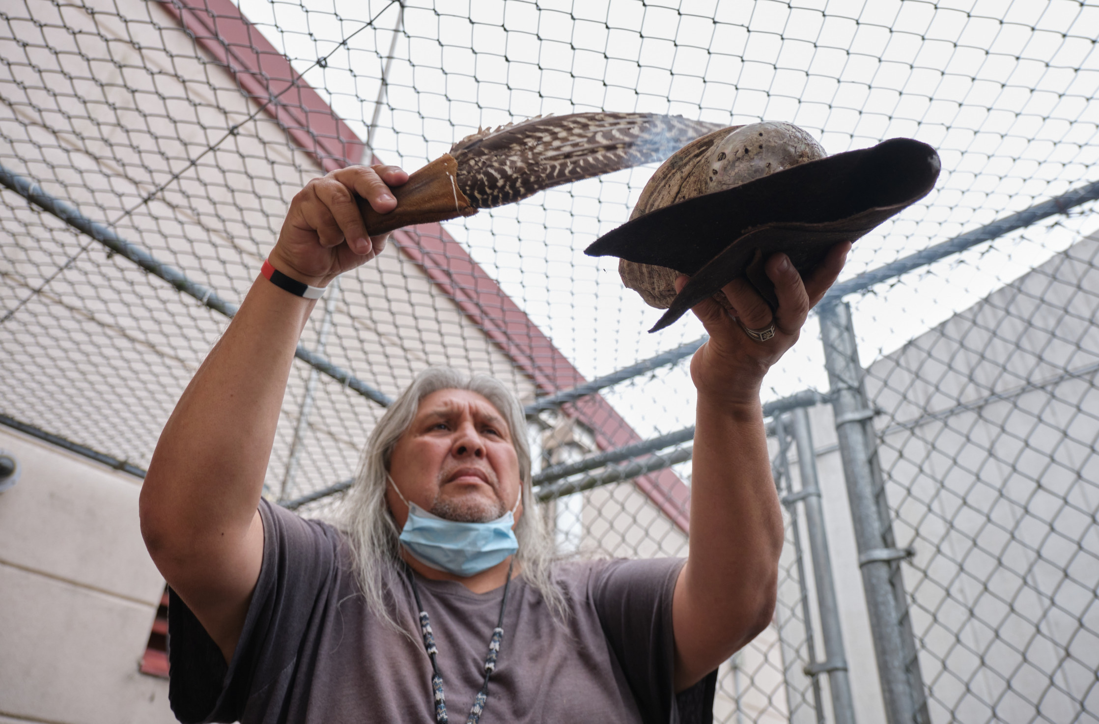 Native American rituals: Native American relder man with long gray hair ho,ding plate of smoking dage and using eagle feather to disperse the smoke