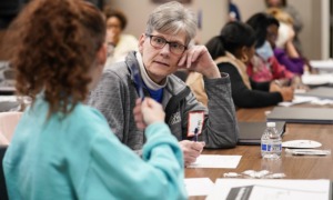 Nonprofits scramble for help amid dearth of volunteers: older person with gray hair and glasses rests head on hand while talking to someone