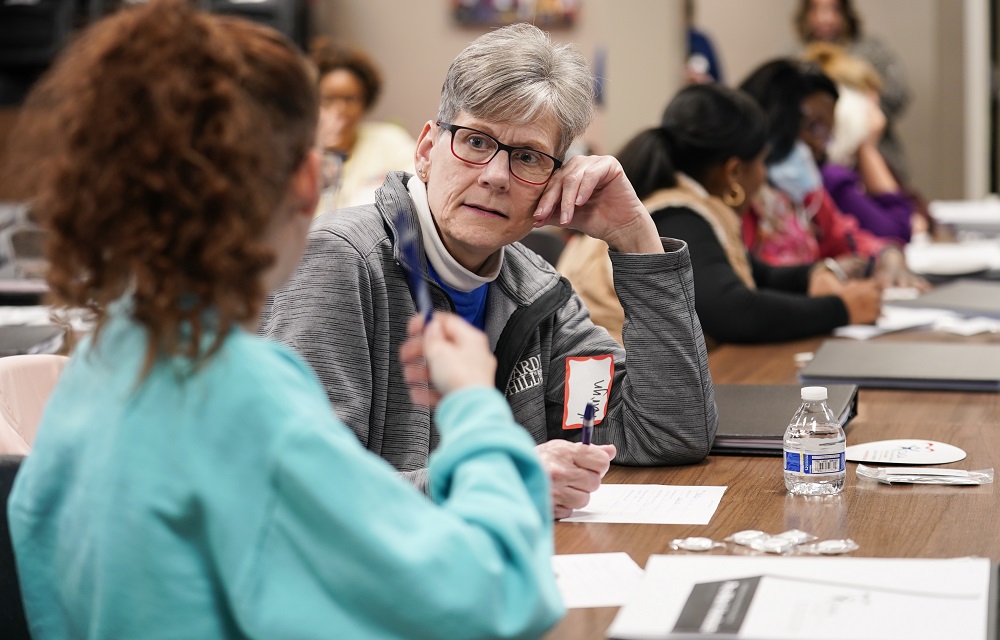 Nonprofits scramble for help amid dearth of volunteers: older person with gray hair and glasses rests head on hand while talking to someone