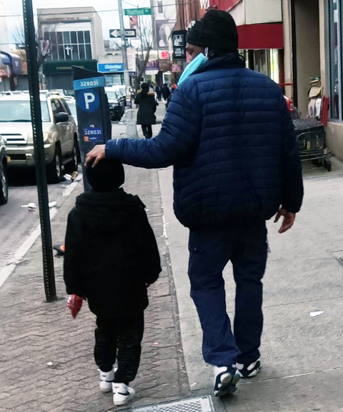 Foster Care Child Removal: Adult and young child both dressed in dark pants and winter jackets walking away from camera on car-lined city sidewalk