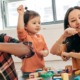 Children's education, arts, community grants: two women and two children happily playing with block toys