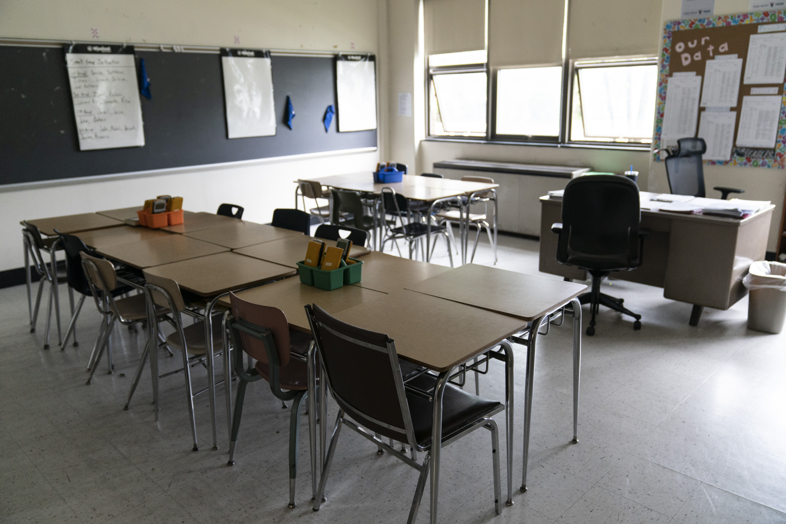 Teacher Salaries; Long shot of classroom full of empty desks.