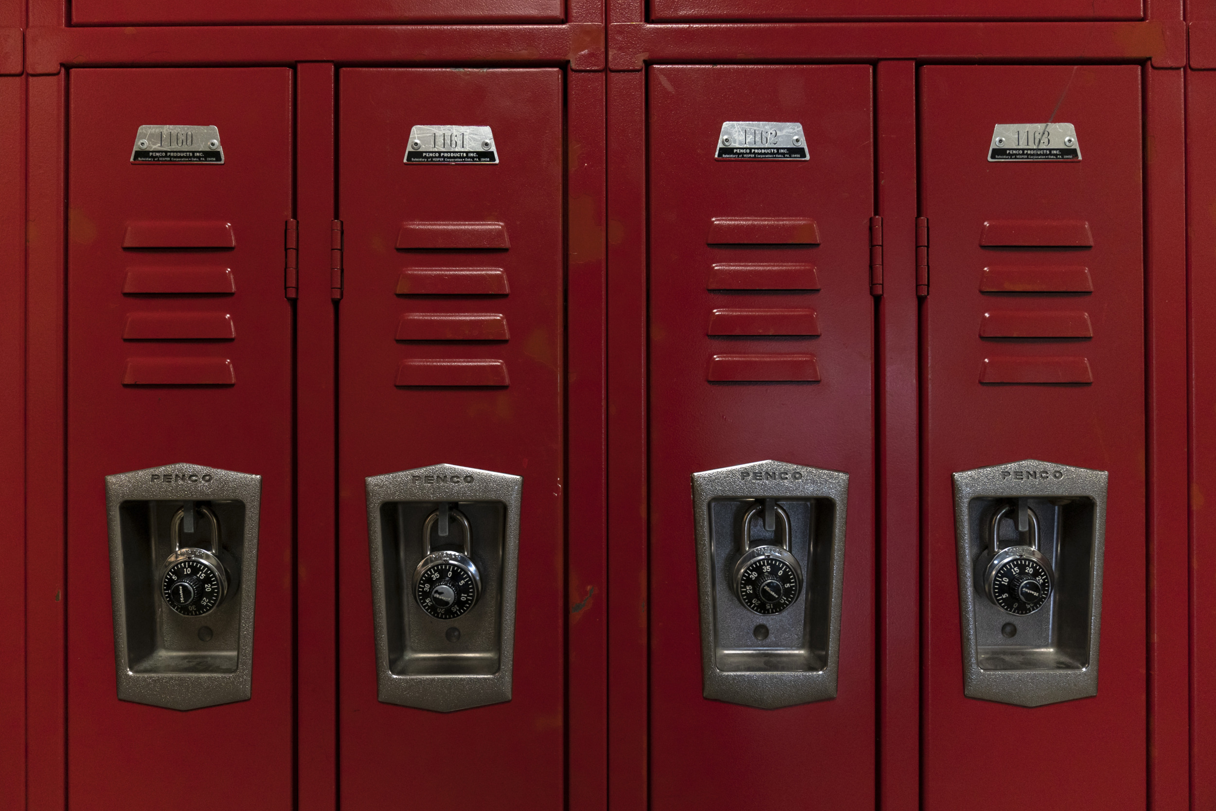 Teacher Salaries: Closeup of red metal locker doors with paslocks.