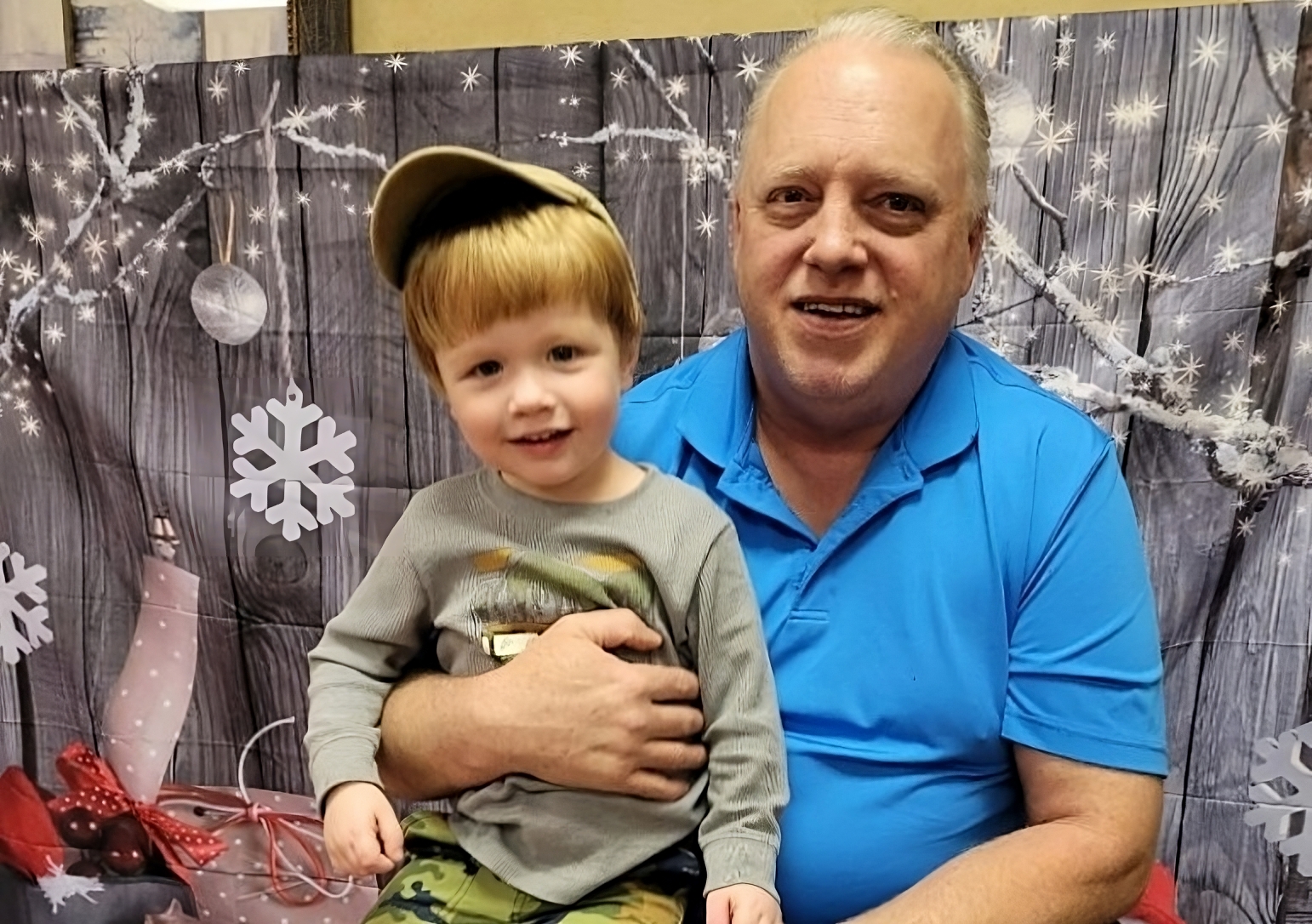 Family First program: older man in blue shirt holding smiling child wearing hat on lap