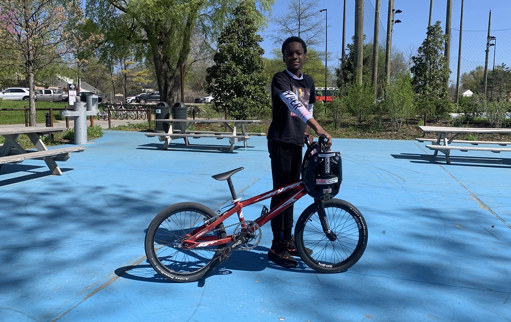New BMX program teaches North Tulsa kids about bikes, racing and resilience: young black kid poses with his BMX bike outdoors