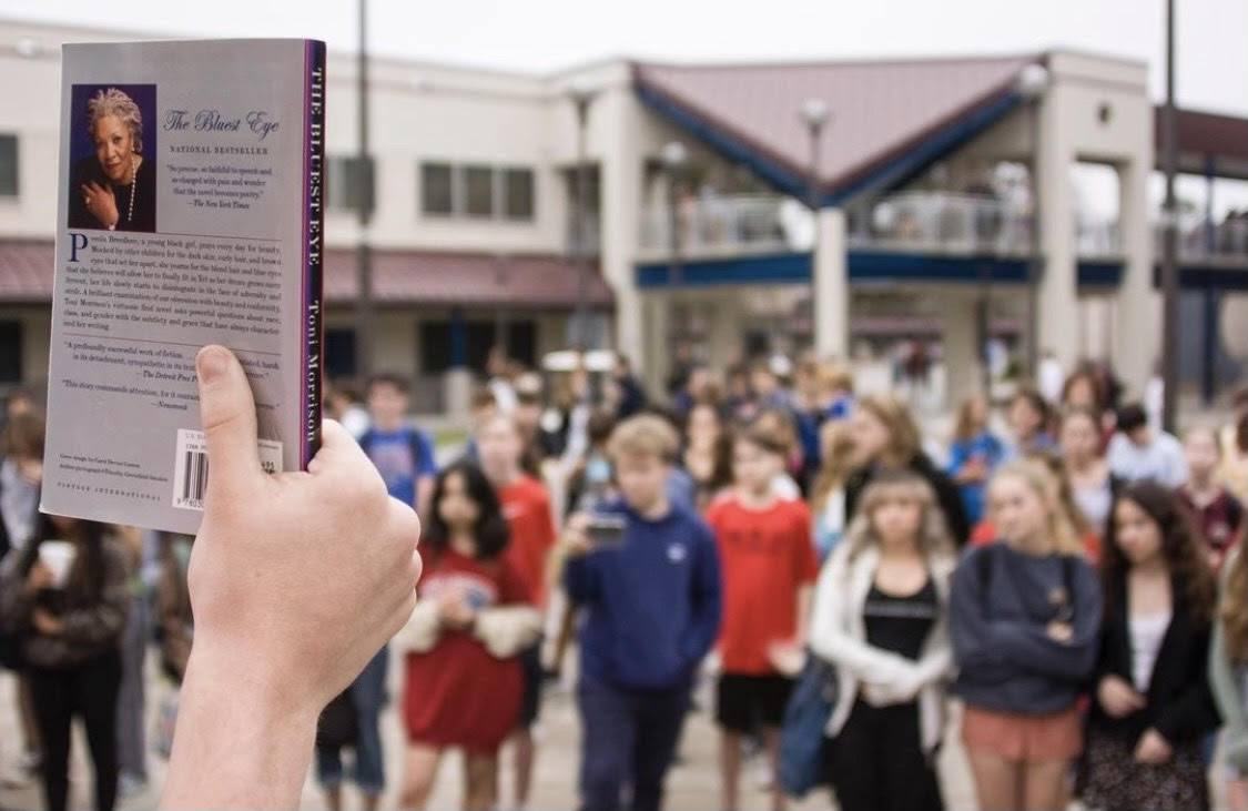 Book bans: a copy of "The Bluest Eye" is held in front of a group of students.