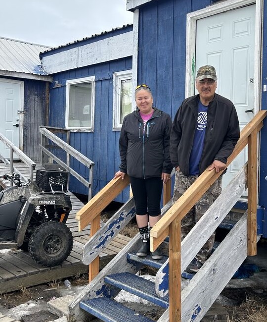 afterschool program in the arctic: man and woman stand on front steps of home with atv off to their right