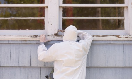 EPA proposes lower lead exposure limit in daycares, homes: person in hazmat suit painting the exterior window sill of older home