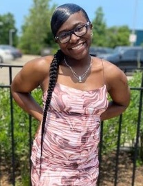 Makaya Massey: young black woman with long braid and glasses smiles outside