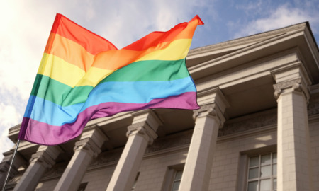 LGBTQ+ youth, students and Title IX: Rainbow flag closeup with traditional style, pillared building in the background