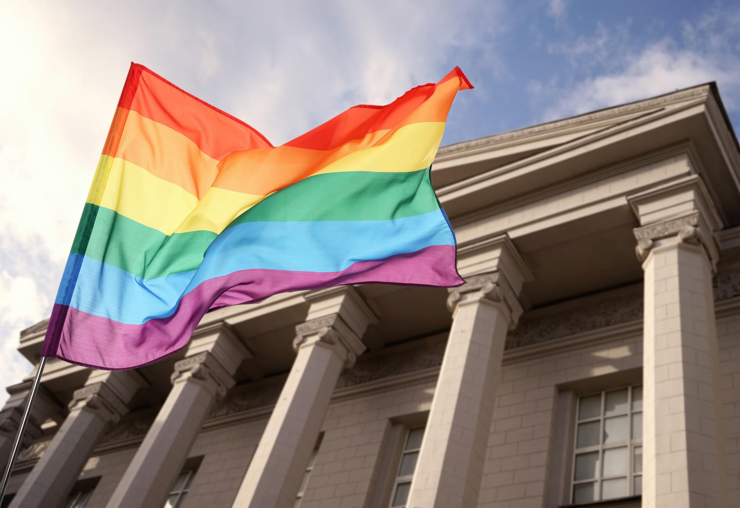 LGBTQ+ Youth: Rainbow flag closeup with traditional style, pillared building in the background