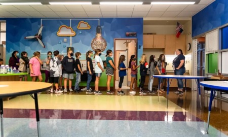 Texas schools are breaking bank to pay for teacher raises: students line up to walk behind teacher in front of colorful wall
