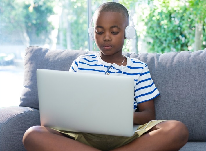 internet crimes against children, child/youth internet safety improvement grants: young black boy on laptop with headphones on