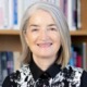 Ellen Alberding steps down from Joyce Foundation: older white woman with mid-length gray hair smiling in front of book-shelves