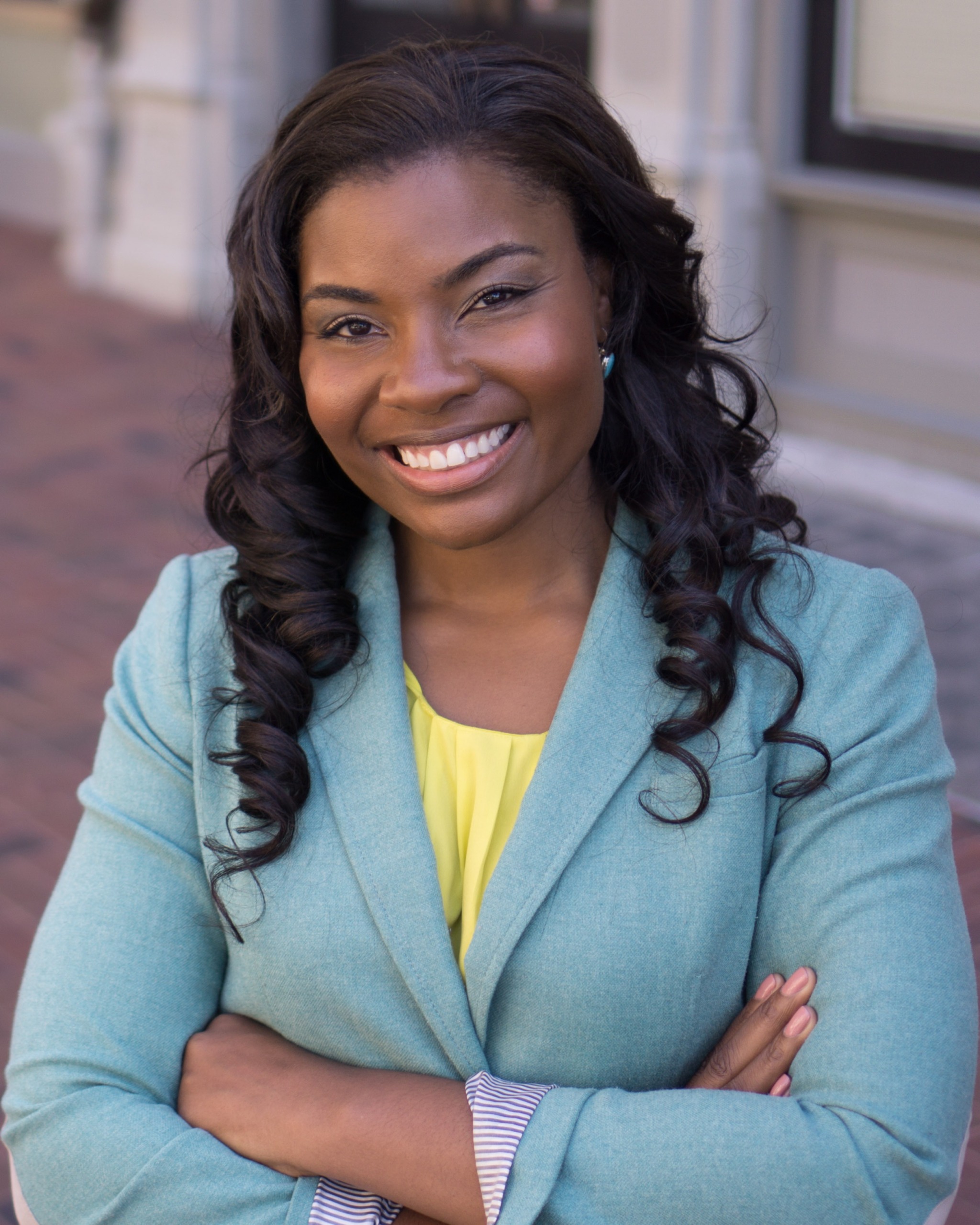 Nikole Collins-Puri headshot: black woman with long hair in blazer smiling outdoors