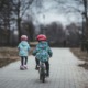Poor rural kids earn more than poor urban; two-parent household may be the reason: two children riding a bike and scooter down pathway in cold weather