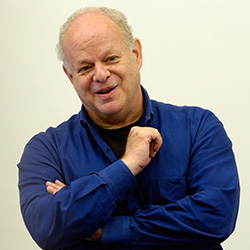 Psychology of happiness: Dr. Martin Seligman, older man with gray hair in navy blue shirt smiling into camera.