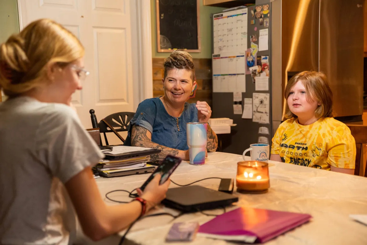 LGBTQ+ Clubs Kentucky: Three people sit around a kitchen table covered with books and notebooks