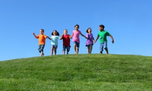 child opportunity report: happy children running over grassy hilltop towards camera