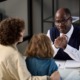 How Cuyahoga County picks attorneys to represent children: middle-aged black man with glasses talks seriously to mother and child across desk