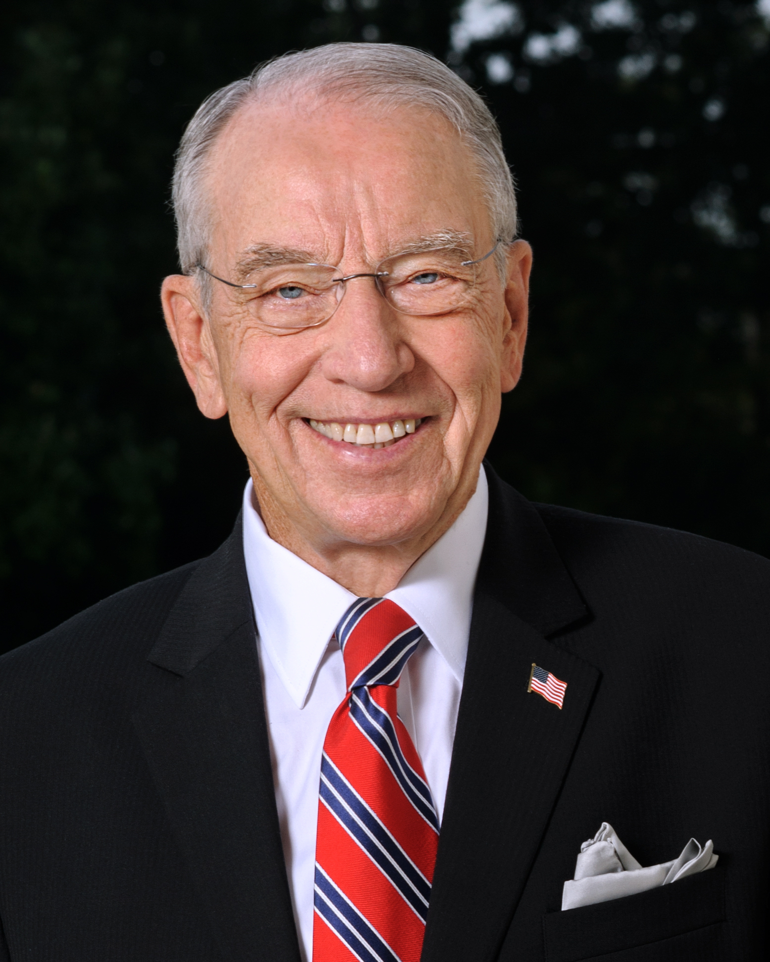 FASFA Farm: Headshot of older man with gray hair in black suit, white shirt and red/blue striped tie smiling broadly into camera.