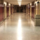 K-12 enrollment decline: Empty school hallway with yellow walls and tan floor lined with brown metal lockers