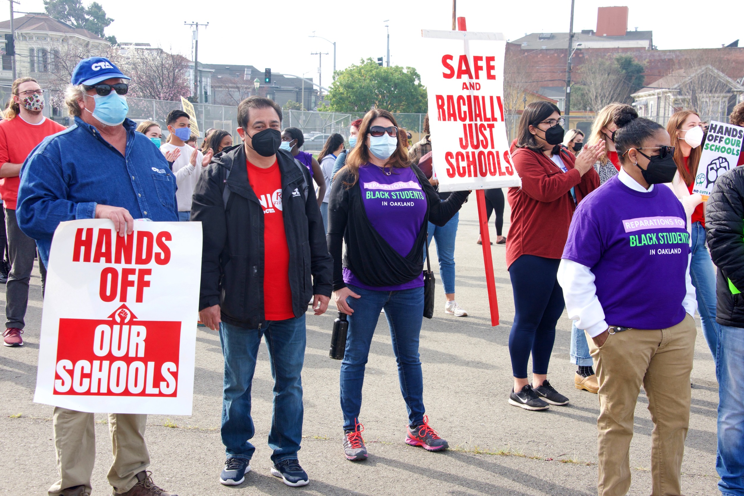 k-12 enrollment decline: Groups of adults stand in street with protest signs
