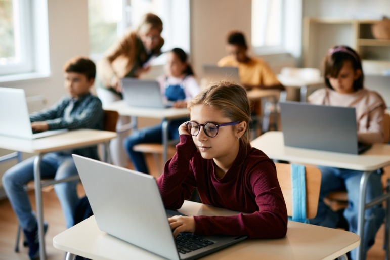 Federal Technology in Education Report: Several elementary students sit at desks working in laptops 