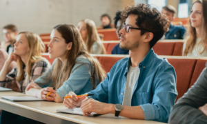 college students remedial courses: Several college students sit at rows of desks on risers