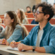 college students remedial courses: Several college students sit at rows of desks on risers