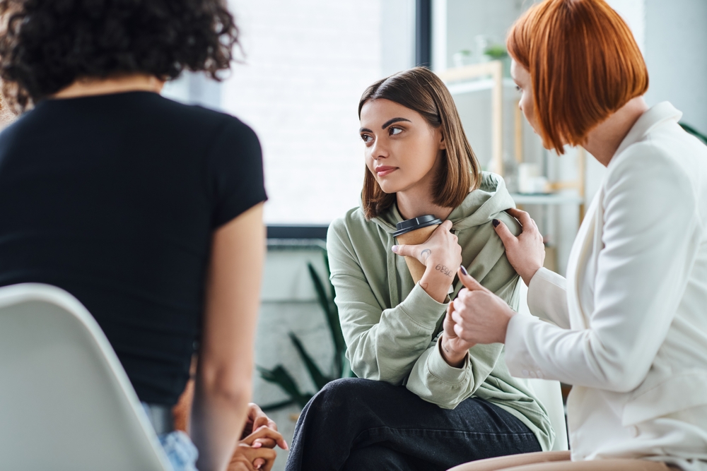college affordability, student mental health: A few college students sit in a close circle with a counselor.
