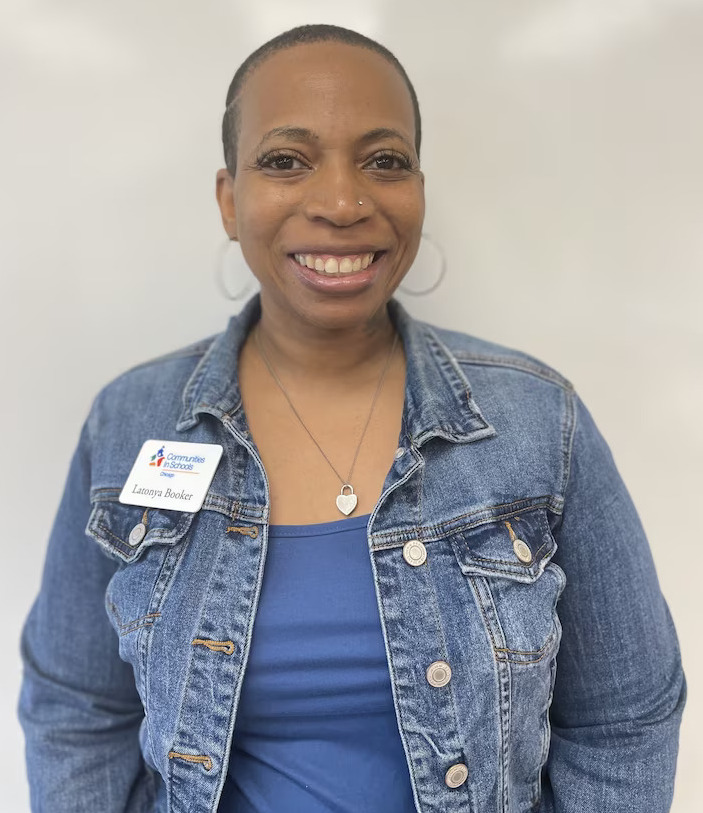 Shooting trauma counselor: Headshot of Black woman with bald head in blue denim jean jacket and blue top smiling into camera